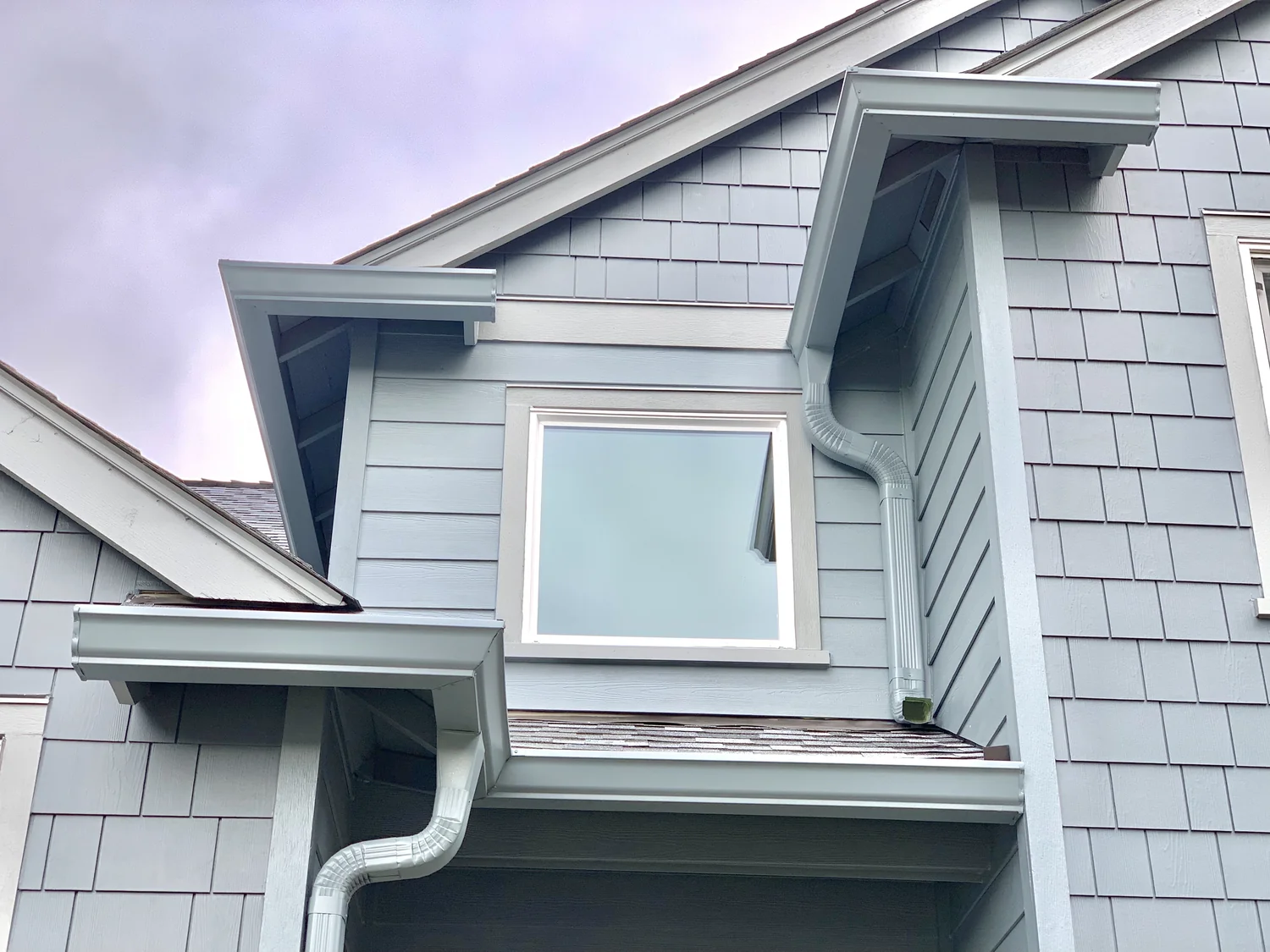 Two-story home with white gutters and roof drainage in the Albany area