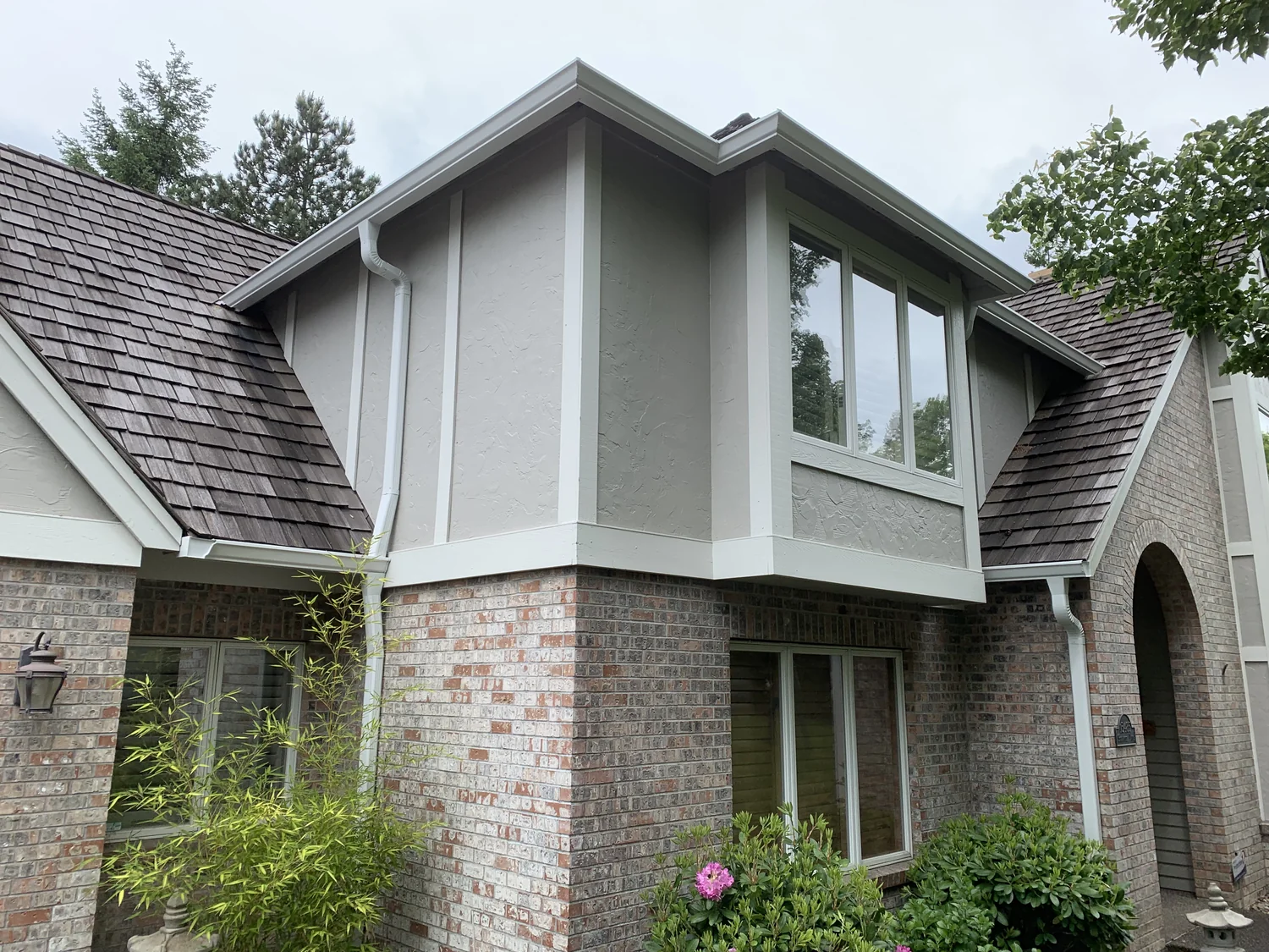 Green downspout and elbow at a brick porch in the Canby area