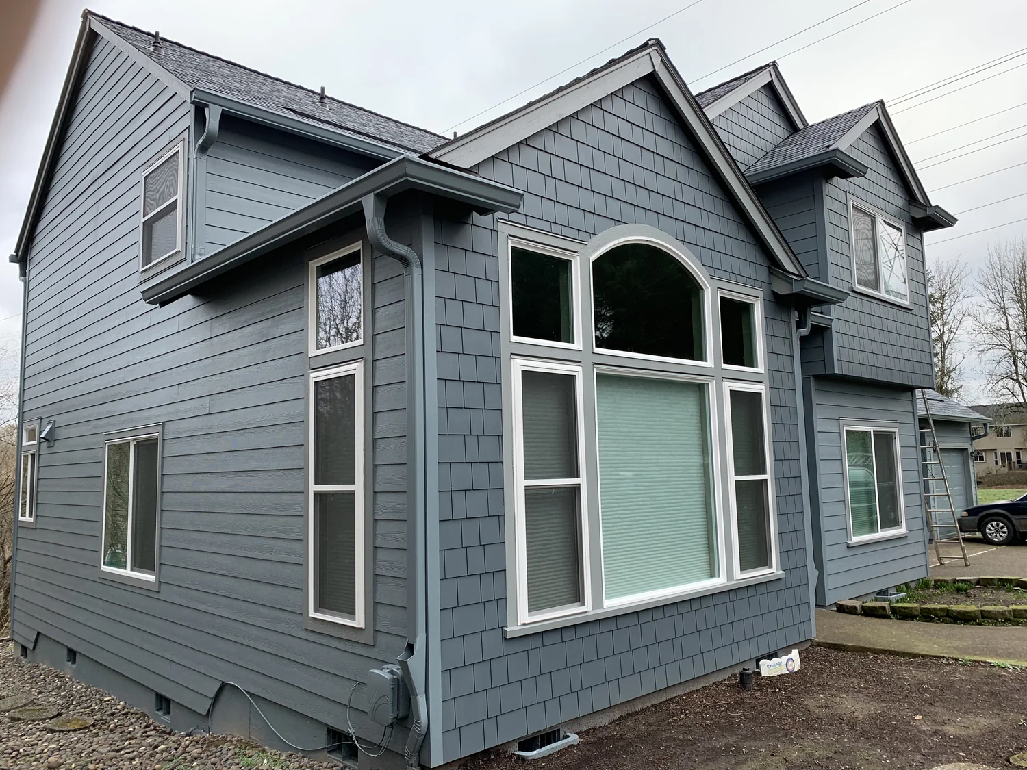 Two-story home with white gutters and autumn leaves in Forest Grove