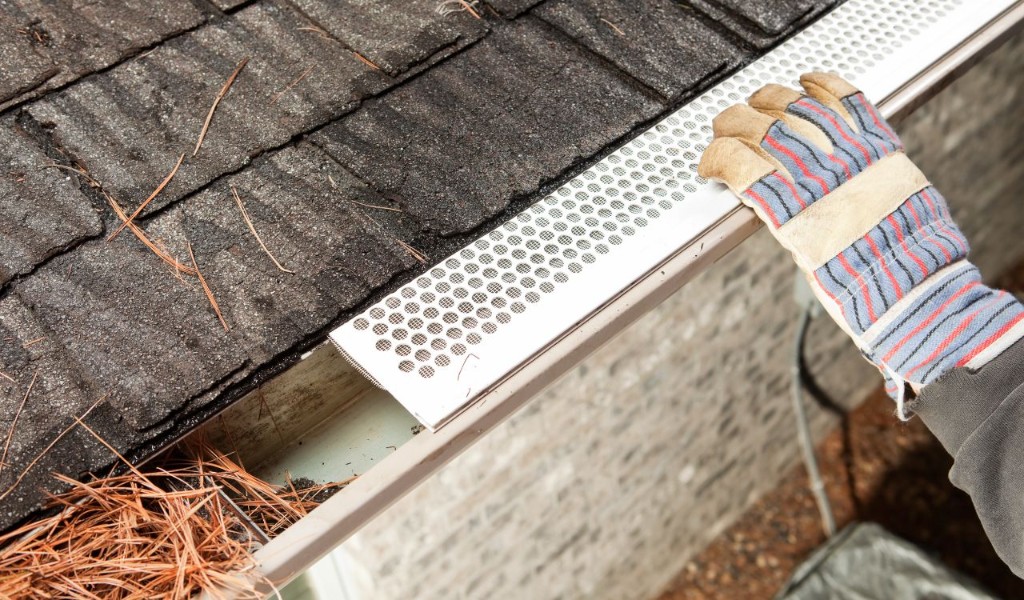 Perforated metal gutter guard installed over pine needles in a residential gutter